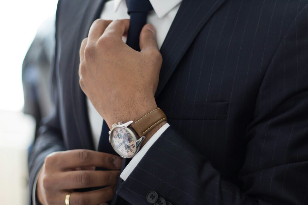 Luxury item like a suit, tie, and watch being carefully worn.